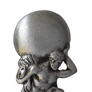 Könnte beinhalten: Silberfarbene Figur, die Atlas darstellt, eine Figur aus der griechischen Mythologie, die eine große Kugel auf seinen Schultern trägt. Die Skulptur zeigt Atlas kniend, mit detaillierter Muskulatur und Gesichtszügen. Klassisches Design.