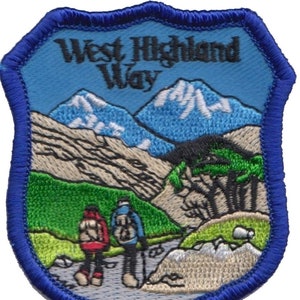 May include: Embroidered patch with a blue background and the text "West Highland Way". The patch depicts a mountain scene with two hikers walking on a path.