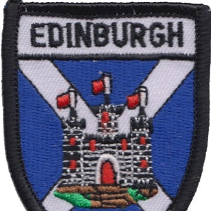 May include: Embroidered patch with a blue background, a white cross, and a black castle with red accents. The text "EDINBURGH" is at the top of the patch.