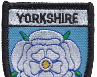 May include: A blue and white embroidered patch with the word "YORKSHIRE" in black lettering and a white rose with a yellow center.