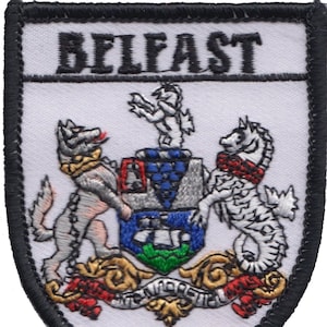 Op de afbeelding: Geborduurde patch met het woord "BELFAST" bovenaan. De patch toont een gedetailleerd wapenschild met fabeldieren, een schild en andere symbolen, tegen een witte achtergrond met een zwarte rand.