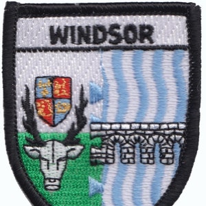 Peut inclure: Un écusson brodé noir et blanc avec le mot "WINDSOR" en haut. L'écusson présente un fond vert avec une tête de cerf blanche, un fond bleu et blanc avec un pont blanc et un écu rouge, blanc et bleu.