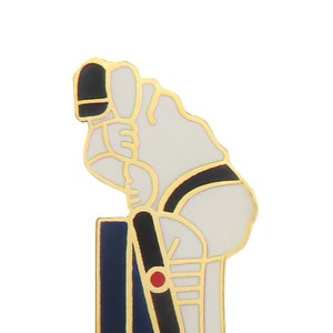 Könnte beinhalten: Eine goldfarbene Emaille-Anstecknadel, die einen Cricketspieler in weißer Uniform mit schwarzem Gürtel zeigt, der einen Schläger hält und in einer Schlagposition steht. Der Spieler trägt einen schwarzen Helm und rote und schwarze Schienbeinschoner. Die Anstecknadel ist vor einem weißen Hintergrund platziert.