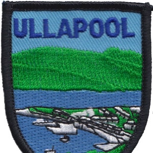 May include: Embroidered patch with a blue background and the text "ULLAPOOL" in white. The patch features a green hill, a blue body of water, and a white shoreline.