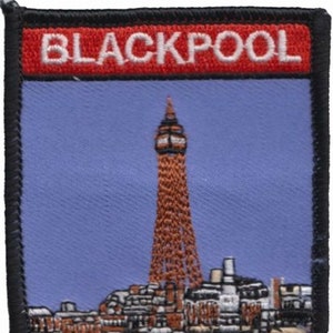 May include: Blackpool embroidered patch featuring a red banner with the text "BLACKPOOL" and an image of the Blackpool Tower.