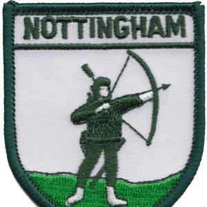 May include: Embroidered patch with the word "NOTTINGHAM" at the top. It depicts an archer in dark green, drawing a bow. The design is on a white background, with a green border and a green grassy area at the bottom.