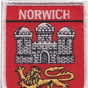 May include: A red embroidered patch with white stitching. The patch features a white castle with three towers and a gold lion. The text "NORWICH" is written in white at the top of the patch.
