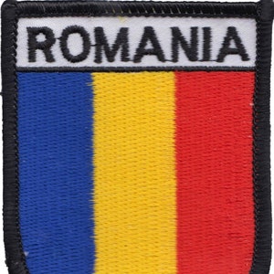 May include: A blue, yellow and red embroidered patch with the word "ROMANIA" in black lettering on a white background.