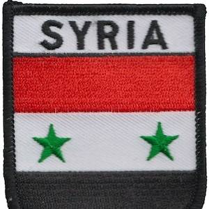 May include: A black, red, white and green embroidered patch with the word "SYRIA" in black lettering and two green five-pointed stars.