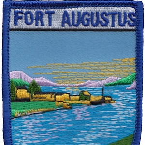 May include: Embroidered patch with a blue border and a white banner that reads "FORT AUGUSTUS". The patch depicts a landscape with a river, mountains, and a building in the foreground.