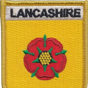 May include: A yellow embroidered patch with a red rose and green leaves. The text "LANCASHIRE" is embroidered in black on a white background at the top of the patch.