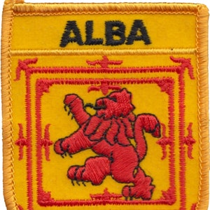 May include: A yellow and red embroidered patch with the word "ALBA" in black lettering. The patch features a red lion rampant within a red frame.