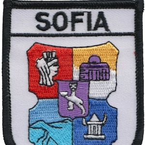 May include: A white embroidered patch with a black border. The patch features the word "SOFIA" at the top and a colorful coat of arms with a purple, white, red, and blue design.