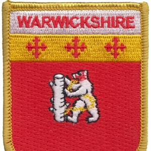 May include: A red and gold embroidered patch with the text "WARWICKSHIRE" in white. The patch features a white bear holding a tree trunk, and three gold crosses.