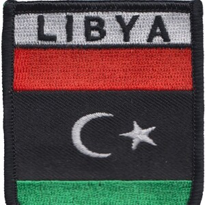 May include: A black, red, green and white embroidered patch with the word "LIBYA" in white letters and a white crescent moon and star on a black background.