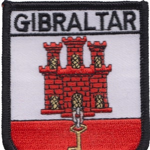 May include: A red, white, and gold embroidered patch with the word "GIBRALTAR" at the top. The patch features a red castle with three towers and a gold key.