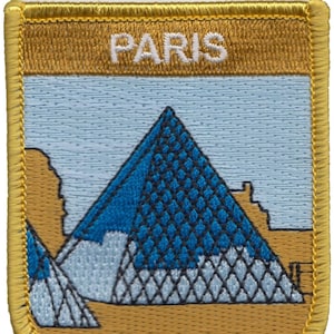 以下が含まれることがあります： 金色の刺繍パッチで、青と白のピラミッドと白い文字で「PARIS」と書かれています。