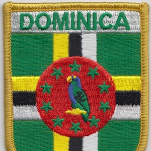 Puede incluir: Parche bordado con la bandera de Dominica. La bandera es verde, amarilla, negra y blanca con un círculo rojo que contiene un loro y estrellas. El texto "DOMINICA" está bordado en blanco sobre un fondo verde.
