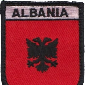 May include: A red embroidered patch featuring a black double-headed eagle and the word "ALBANIA" in white lettering.