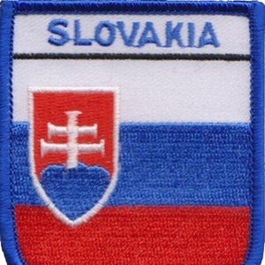 Op de afbeelding: Een blauwe, witte en rode geborduurde patch met het woord "SLOVAKIA" in blauwe letters. De patch toont het Slowaakse wapen, een wit dubbel kruis op een rood schild, binnen een blauw schild.