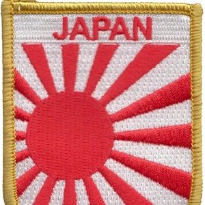Puede incluir: Un parche bordado blanco con un sol naciente rojo y la palabra "JAPÓN" en letras doradas. El parche tiene un borde dorado.