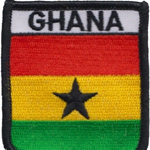 Puede incluir: Un parche bordado en blanco y negro con la palabra "GHANA" en letras negras sobre un fondo blanco. El parche presenta la bandera de Ghana con rayas horizontales rojas, amarillas y verdes y una estrella negra de cinco puntas en el centro de la raya amarilla.