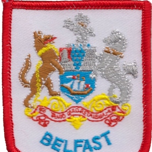 May include: A white embroidered patch with a red border. The patch features a coat of arms with a ship, a wolf, and a unicorn. The text "BELFAST" is written in blue below the coat of arms.