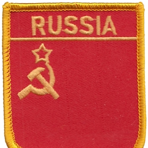 May include: Embroidered patch featuring the word "RUSSIA" in gold thread above a gold hammer and sickle with a star on a red background. The patch has a gold border.