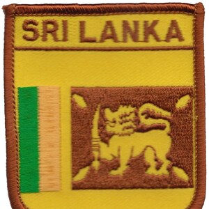 May include: A brown embroidered patch with the words "SRI LANKA" in brown lettering. The patch features a yellow background with a green and orange vertical stripe on the left side and a brown lion with a sword in its paw on the right side.
