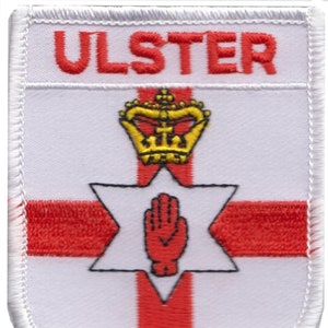 Puede incluir: Un parche blanco con una cruz roja y una mano roja en una estrella de seis puntas. La palabra "ULSTER" está en la parte superior del parche.