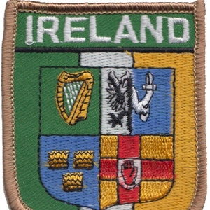 Puede incluir: Un parche bordado en verde, blanco y dorado con la palabra "IRELAND" en letras blancas. El parche presenta un escudo con un arpa, un pájaro y una mano.