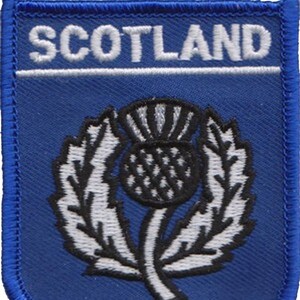 Peut inclure: Un écusson brodé bleu avec des coutures blanches. L'écusson représente un chardon blanc avec une tige et des feuilles noires. Le mot "SCOTLAND" est écrit en lettres blanches en haut de l'écusson.