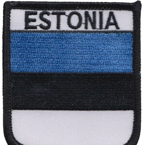 May include: An embroidered patch featuring the Estonian flag. The flag is blue, black, and white with the word "ESTONIA" in black lettering at the top.