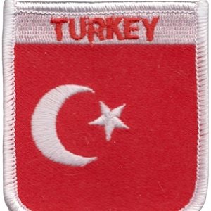 May include: A red, white, and cream-colored patch featuring the flag of Turkey. The patch has a shield shape with a white crescent moon and star on a red background. The word "TURKEY" is embroidered in red.