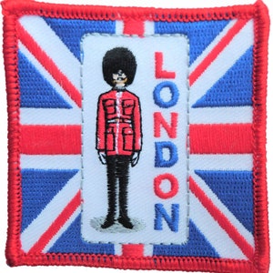 May include: A red, white, and blue embroidered patch with a cartoon image of a British guard in a red uniform and a black bearskin hat. The word "LONDON" is embroidered vertically on the right side of the patch.