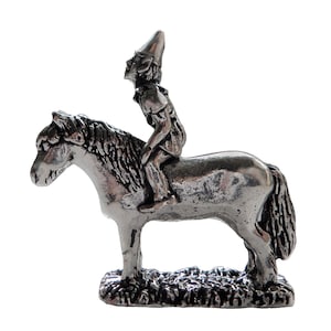 Könnte beinhalten: Eine silberne Figur eines Reiters auf einem Pferd. Die Person trägt einen spitzen Hut und sitzt auf dem Rücken des Pferdes. Das Pferd hat eine lange Mähne und einen langen Schweif.