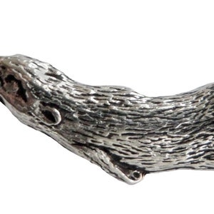 Könnte beinhalten: Eine silberfarbene Zinnfigur eines Otters. Der Otter ist beim Schwimmen dargestellt, mit dem Kopf zur Seite gedreht und dem Schwanz eingerollt.