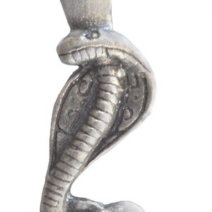 May include: A silver-coloured pewter pendant featuring a cobra with a crown on its head. The cobra is depicted in a coiled position with its head raised and its fangs bared.