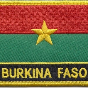 Może przedstawiać: Naszywka haftowana w kolorze czerwonym, zielonym i żółtym z żółtą gwiazdą w środku i napisem "BURKINA FASO" żółtymi literami na czarnym tle.