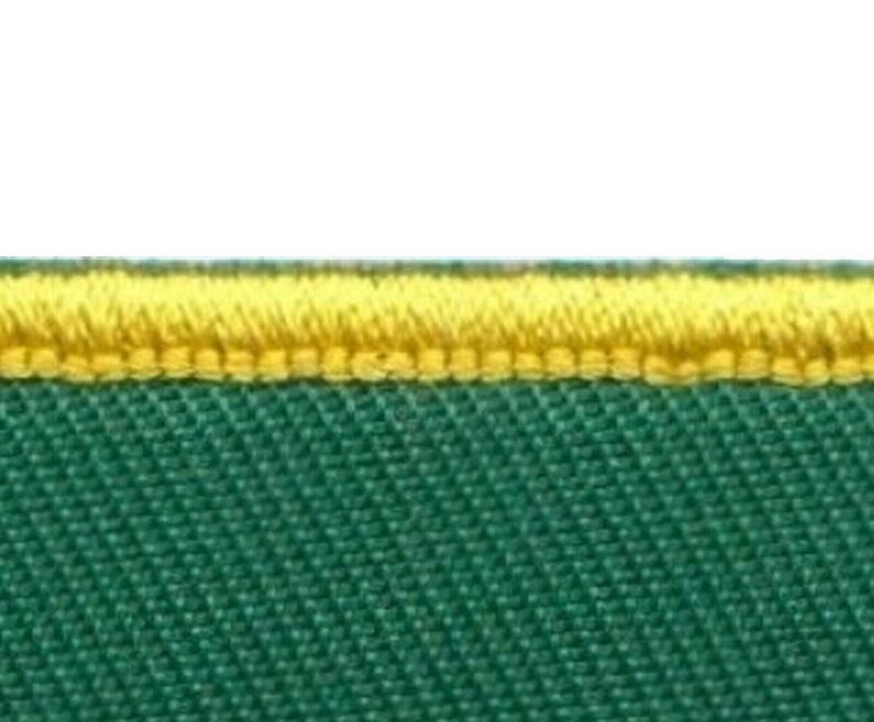 May include: Close-up of a green fabric with a yellow stitched border.