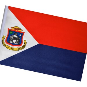 May include: A rectangular flag of Sint Maarten, featuring a red upper section, a blue lower section, and a white triangle with the coat of arms. The coat of arms includes a building, a shield, and text.