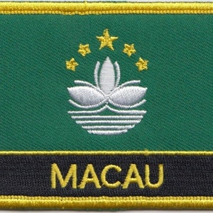 May include: An embroidered patch in green with a white lotus flower and five yellow stars. The patch has a black border and a yellow border around the black border. The text "MACAU" is written in yellow letters on the black border.
