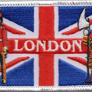 Puede incluir: Parche bordado con un diseño de bandera Union Jack rojo, blanco y azul. Las palabras "LONDON" están bordadas en blanco en el centro de la bandera. Un guardia con uniforme rojo y una figura con una túnica colorida se encuentran a cada lado de la bandera.