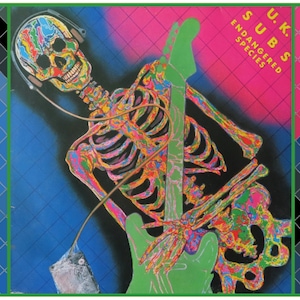 Pode incluir: Uma imagem psicodélica e colorida de um esqueleto tocando uma guitarra elétrica verde. O esqueleto está usando fones de ouvido e tem uma cabeça de caveira. O fundo é um padrão de diamantes rosa e azul com o texto "U.K. SUBS ENDANGERED SPECIES".