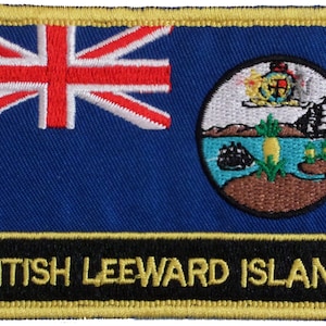 May include: A blue patch with a gold border and the text "BRITISH LEEWARD ISLANDS" in gold letters. The patch features a Union Jack flag on the left and a circular emblem on the right. The emblem depicts a tropical island scene with a pineapple, a ship, and a palm tree.