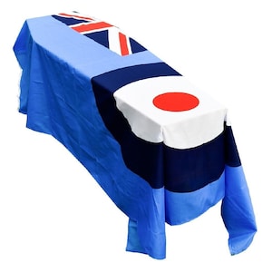 Op de afbeelding: Een blauwe, witte en rode vlag gedrapeerd over een tafel. De vlag heeft een rode cirkel op een witte achtergrond, een blauw veld en een Union Jack in de linkerbovenhoek.