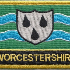 May include: An embroidered patch in green and blue with a white shield and three black teardrops. The text "WORCESTERSHIRE" is embroidered in yellow on a black background.