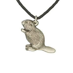 Puede incluir: Un collar con colgante de color plateado con un dije detallado de castor. El castor se representa de pie con la cola extendida. El colgante cuelga de un cordón negro, creando un diseño simple pero llamativo.