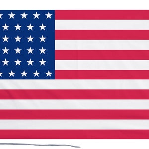 May include: A red, white and blue American flag with 50 white stars on a blue field. The flag is made of fabric and has a white fringe on the left side.