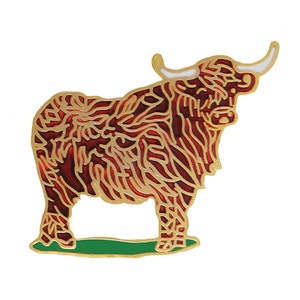 Puede incluir: Un pin de color dorado con un diseño de vaca de las tierras altas roja y dorada. La vaca está de pie sobre una base verde.